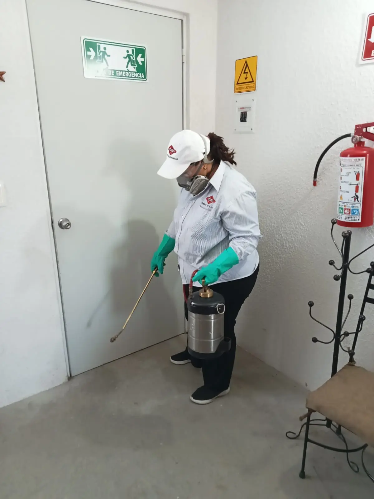 Técnica de FUMIESCAL realizando una aplicación con equipo de protección